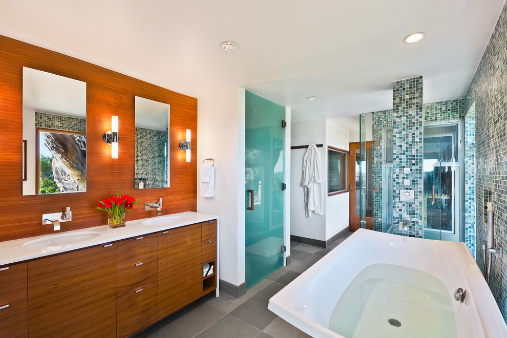 Modernes Badezimmer mit freistehender Badewanne, Duschnische, blauen Fliesen, Mosaikfliesen, flächenbündigen Schrankfronten und hellbraunen Holzschränken in Santa Barbara