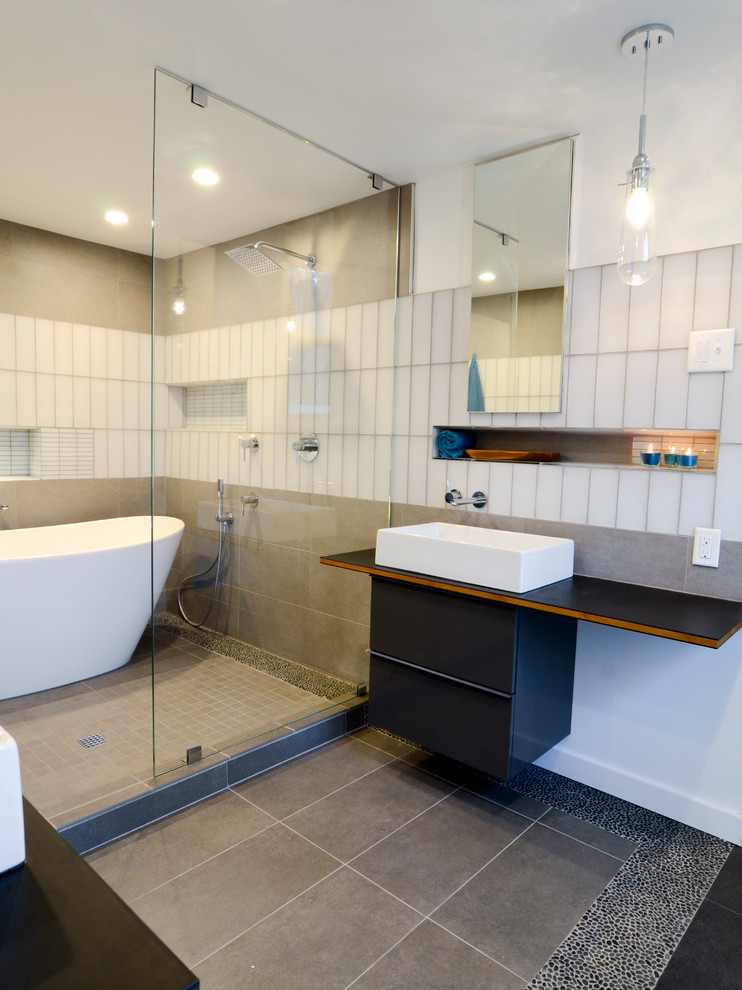 Modern inredning av ett stort en-suite badrum, med släta luckor, grå skåp, ett fristående badkar, våtrum, en vägghängd toalettstol, grå kakel, keramikplattor, vita väggar, klinkergolv i keramik, ett fristående handfat, grått golv, med dusch som är öppen och träbänkskiva