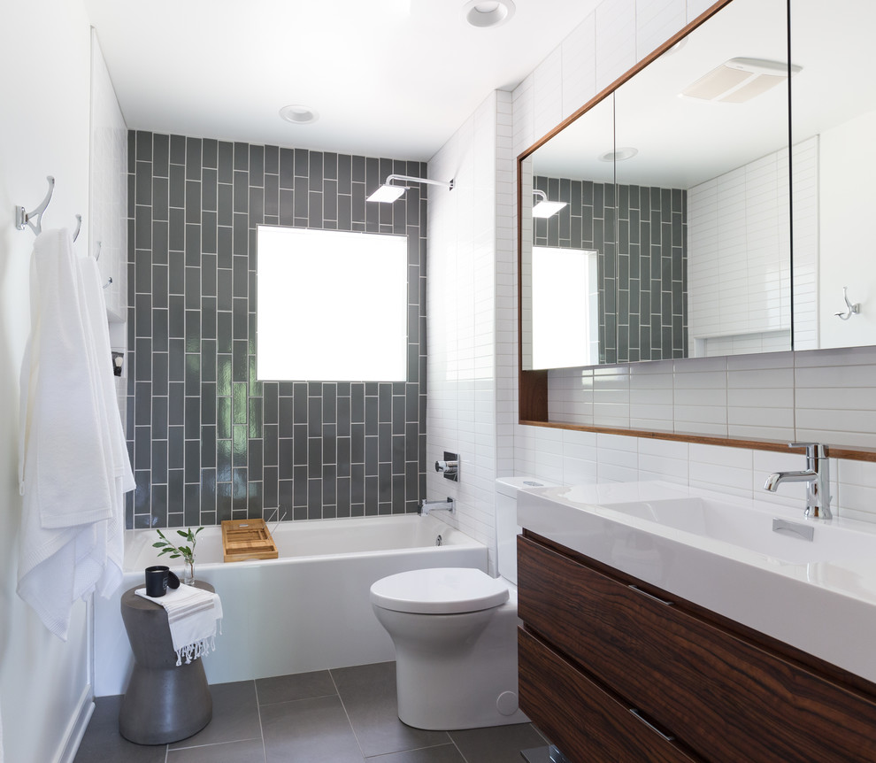 Идея дизайна: ванная комната в современном стиле с плоскими фасадами, темными деревянными фасадами, ванной в нише, душем над ванной, серой плиткой, белой плиткой, белыми стенами, консольной раковиной и серым полом