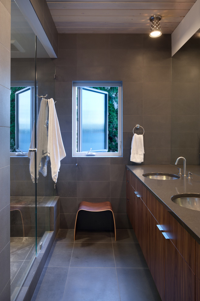 Mid-Century Badezimmer mit Unterbauwaschbecken, grauen Fliesen, grauer Wandfarbe, flächenbündigen Schrankfronten, dunklen Holzschränken, Duschnische, Schieferboden, grauem Boden und Falttür-Duschabtrennung in Seattle