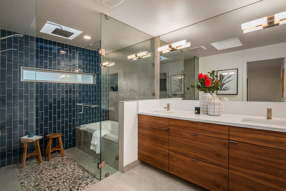 Large retro ensuite wet room bathroom in Seattle with flat-panel cabinets, dark wood cabinets, a built-in bath, porcelain tiles, white walls, porcelain flooring, engineered stone worktops, white floors, a hinged door, white worktops, blue tiles and a submerged sink.
