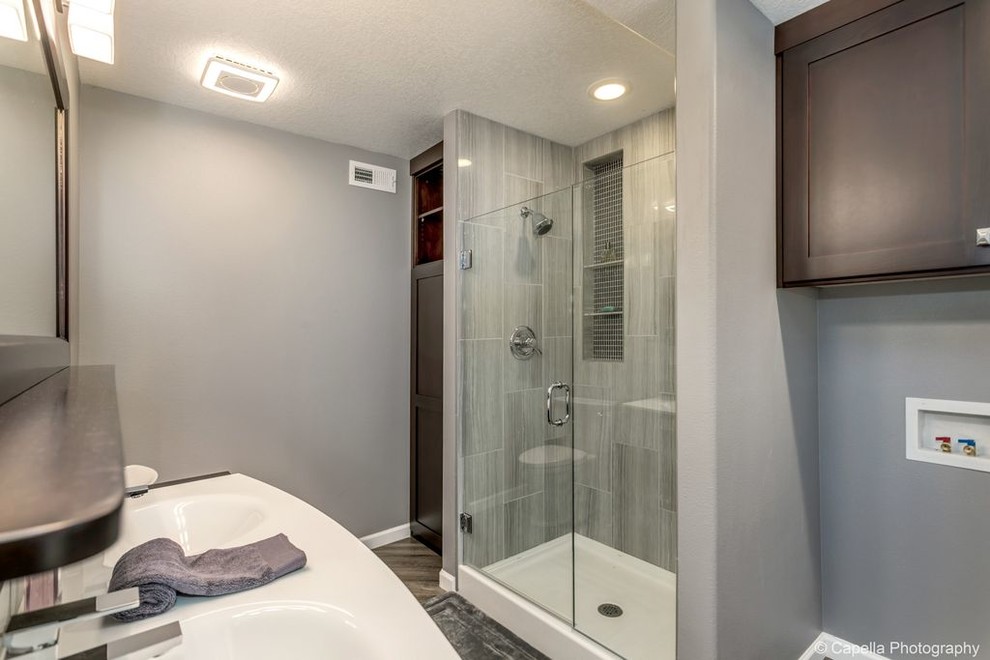 Example of a large mid-century modern gray tile and glass tile vinyl floor and gray floor doorless shower design in Portland with furniture-like cabinets, dark wood cabinets, a two-piece toilet, gray walls, an integrated sink, solid surface countertops, a hinged shower door and white countertops