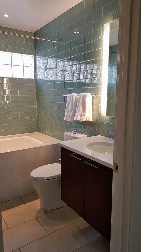 Small modern family bathroom in Cedar Rapids with flat-panel cabinets, dark wood cabinets, a submerged bath, a shower/bath combination, a two-piece toilet, white tiles, glass tiles, green walls, porcelain flooring, a submerged sink, engineered stone worktops, grey floors, a shower curtain and white worktops.