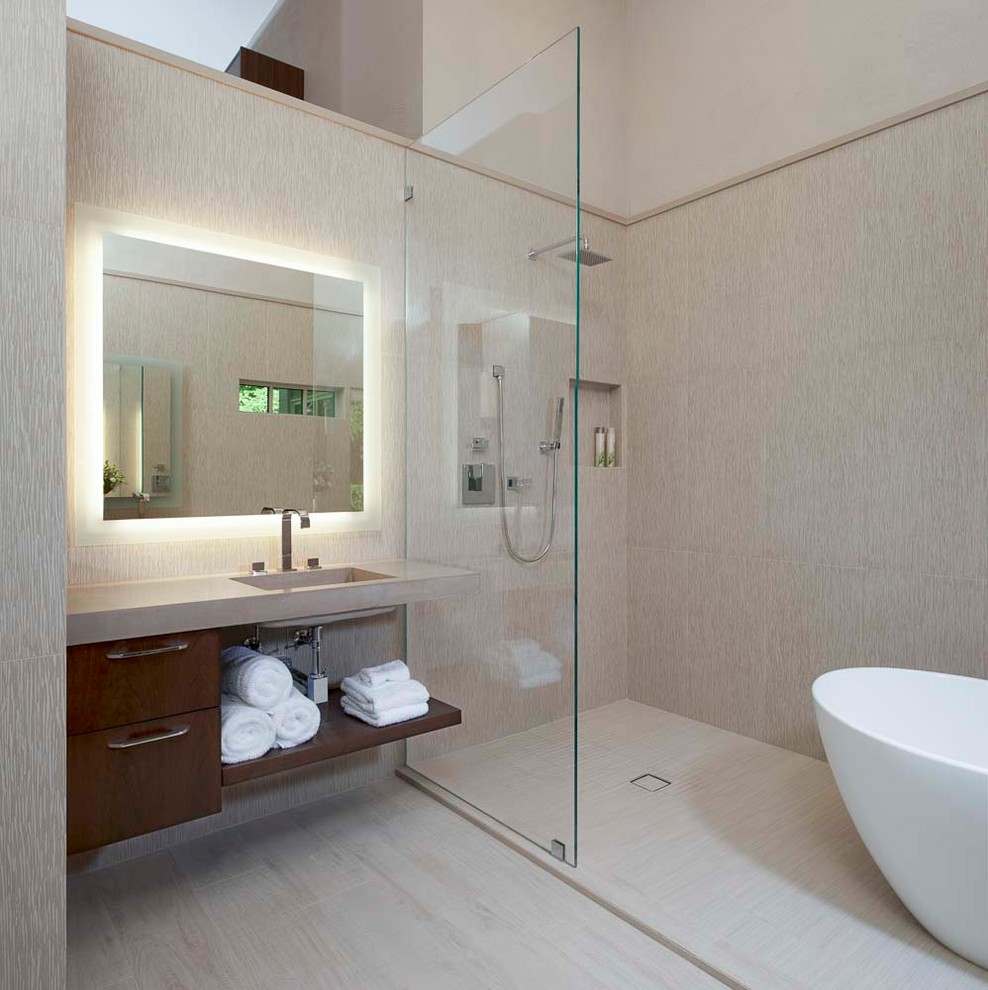 Bild på ett mellanstort retro beige beige en-suite badrum, med släta luckor, bruna skåp, ett fristående badkar, en dusch/badkar-kombination, en toalettstol med hel cisternkåpa, beige kakel, keramikplattor, beige väggar, klinkergolv i keramik, ett integrerad handfat, bänkskiva i betong, beiget golv och med dusch som är öppen