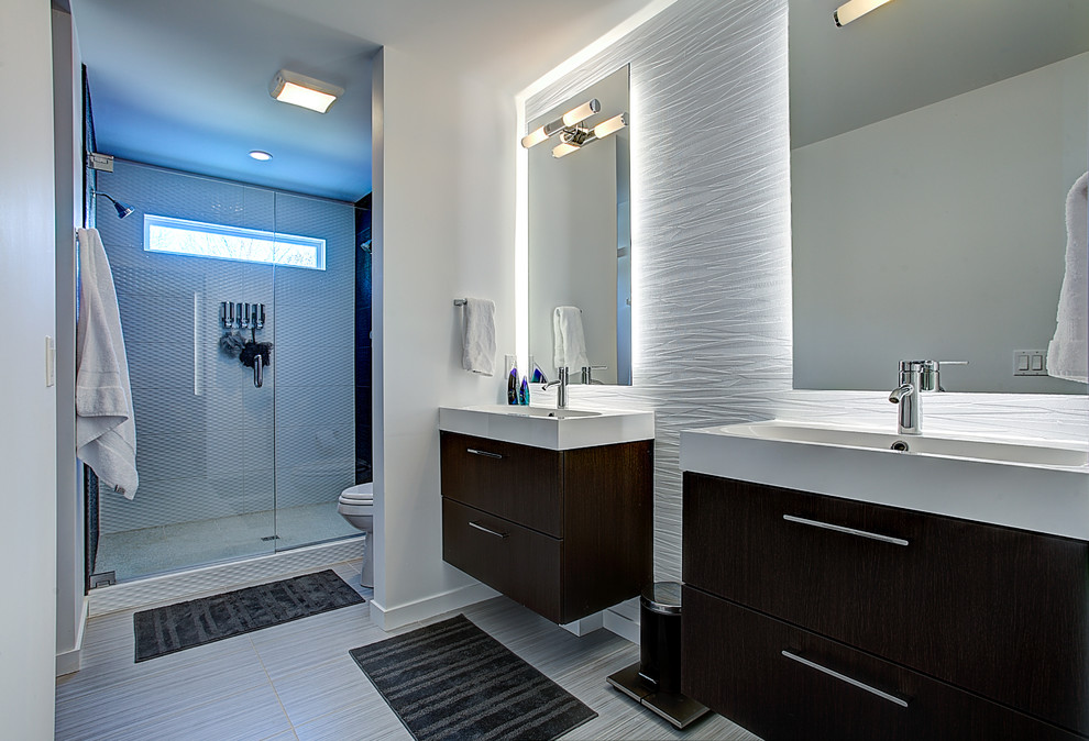 This is an example of a large contemporary ensuite bathroom in Grand Rapids with flat-panel cabinets, dark wood cabinets, solid surface worktops, a walk-in shower, ceramic tiles, white walls, ceramic flooring and a trough sink.