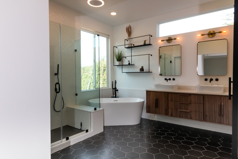 Inspiration for a retro bathroom in Orange County with flat-panel cabinets, brown cabinets, a freestanding bath, a corner shower, black and white tiles, porcelain tiles, white walls, porcelain flooring, a vessel sink, engineered stone worktops, black floors, a hinged door, white worktops, a shower bench, double sinks and a floating vanity unit.