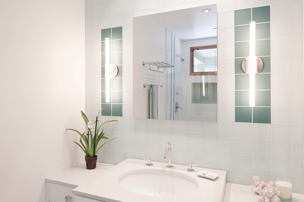 На фото: ванная комната среднего размера в стиле модернизм с плоскими фасадами, белыми фасадами, душем в нише, зеленой плиткой, белой плиткой, стеклянной плиткой, белыми стенами, душевой кабиной, подвесной раковиной и столешницей из искусственного кварца