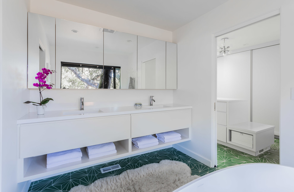 Inredning av ett 60 tals vit vitt en-suite badrum, med släta luckor, vita skåp, cementgolv, bänkskiva i kvarts, grönt golv, vita väggar och ett integrerad handfat