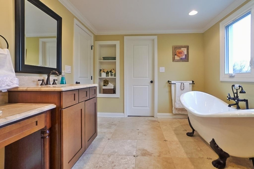 Réalisation d'une salle de bain principale vintage en bois brun avec un placard à porte shaker, une baignoire sur pieds, une douche d'angle, un carrelage beige, du carrelage en pierre calcaire, un mur beige, un sol en calcaire, un lavabo encastré, un plan de toilette en calcaire, un sol beige, une cabine de douche à porte battante, un plan de toilette multicolore, meuble double vasque et meuble-lavabo sur pied.