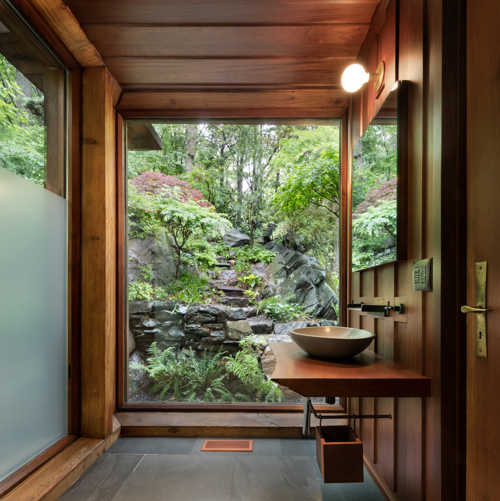 На фото: ванная комната в стиле ретро с настольной раковиной, столешницей из дерева, серым полом и коричневой столешницей с