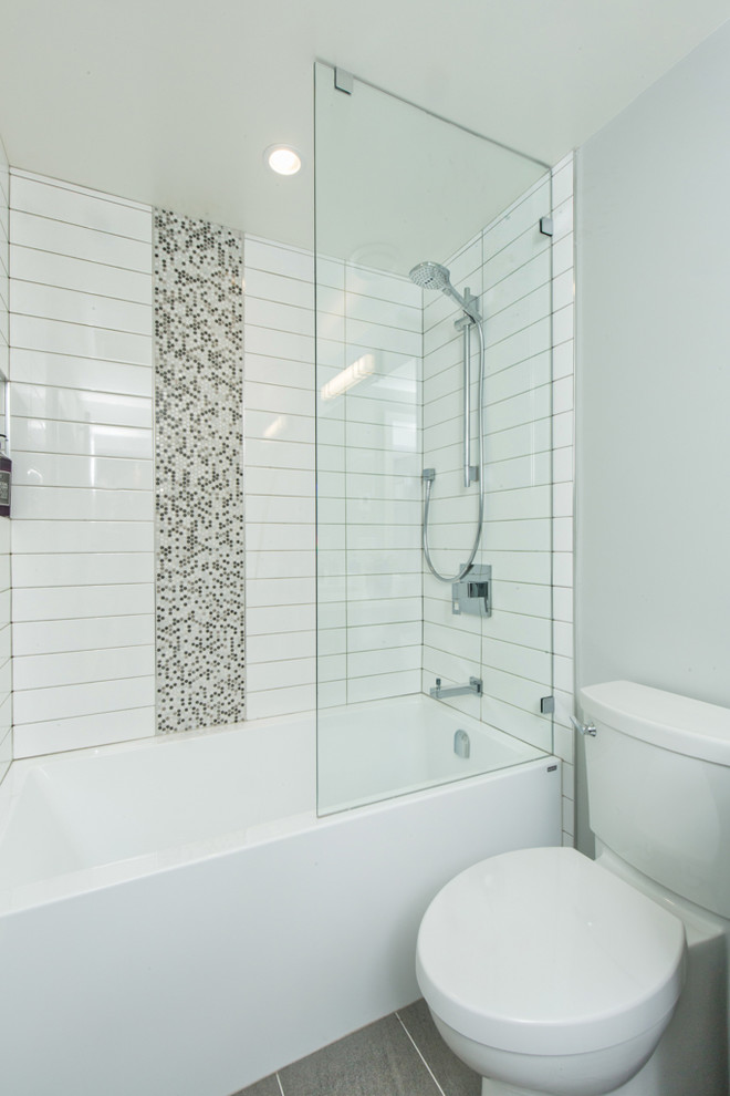 Стильный дизайн: ванная комната среднего размера в стиле модернизм с плоскими фасадами, серыми фасадами, ванной в нише, душем над ванной, раздельным унитазом, серой плиткой, керамогранитной плиткой, серыми стенами, полом из керамогранита, душевой кабиной, накладной раковиной, столешницей из ламината, серым полом и открытым душем - последний тренд