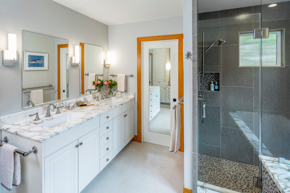 Elegant master gray tile and porcelain tile porcelain tile and beige floor alcove shower photo in Austin with raised-panel cabinets, white cabinets, an undermount sink, marble countertops, a hinged shower door and gray walls