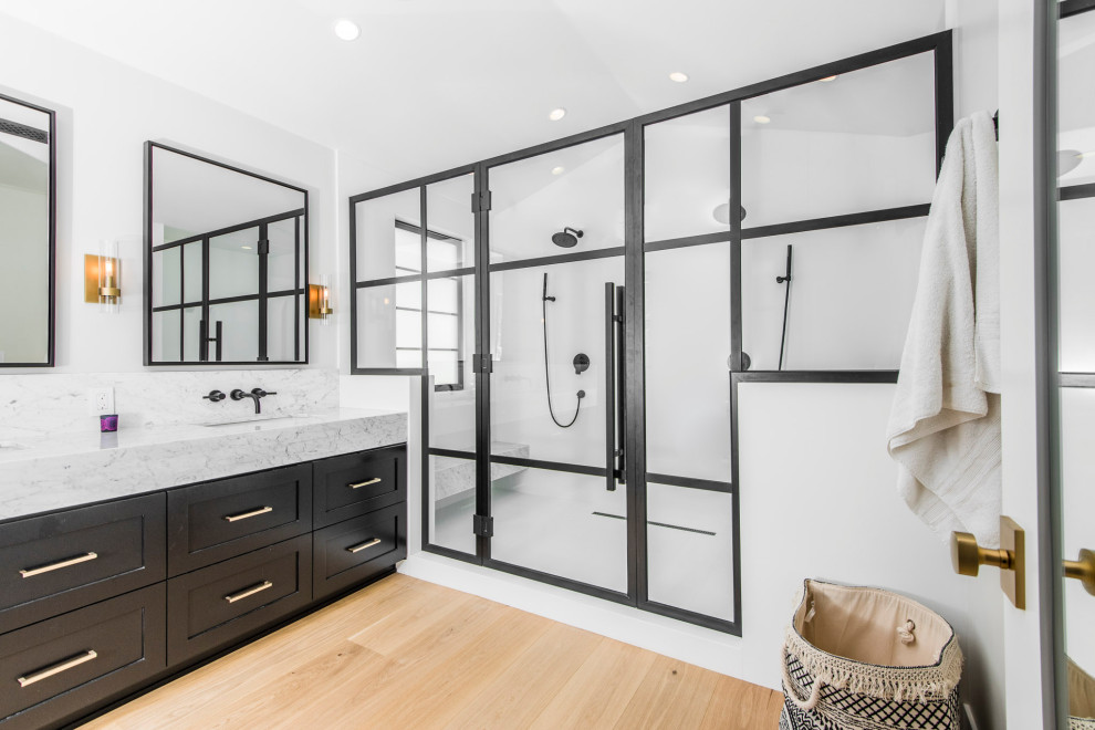 Example of a mid-sized transitional master black and white tile and marble tile light wood floor, brown floor and double-sink bathroom design in Los Angeles with shaker cabinets, black cabinets, a one-piece toilet, white walls, an undermount sink, marble countertops, a hinged shower door, white countertops and a built-in vanity