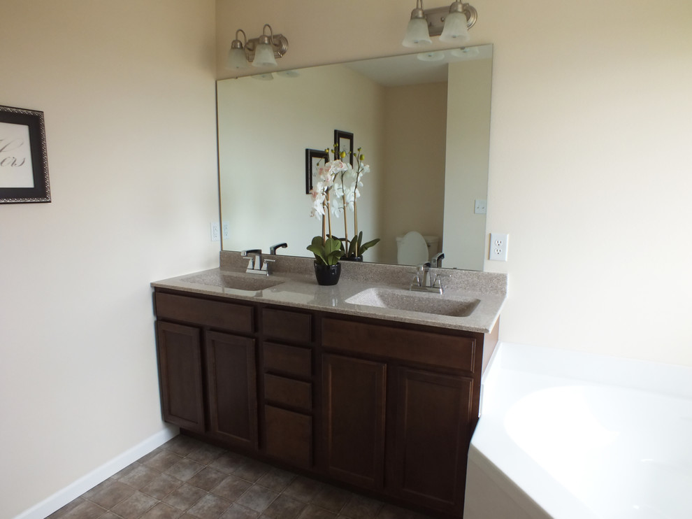 Cette photo montre une salle de bain principale tendance en bois foncé de taille moyenne avec un placard à porte plane, un mur beige, un sol en linoléum, un lavabo intégré et un plan de toilette en marbre.