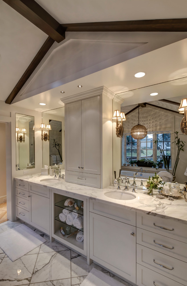 Bathroom - large transitional master white tile and stone tile marble floor bathroom idea in Omaha with an undermount sink, recessed-panel cabinets, white cabinets, marble countertops, a two-piece toilet and white walls