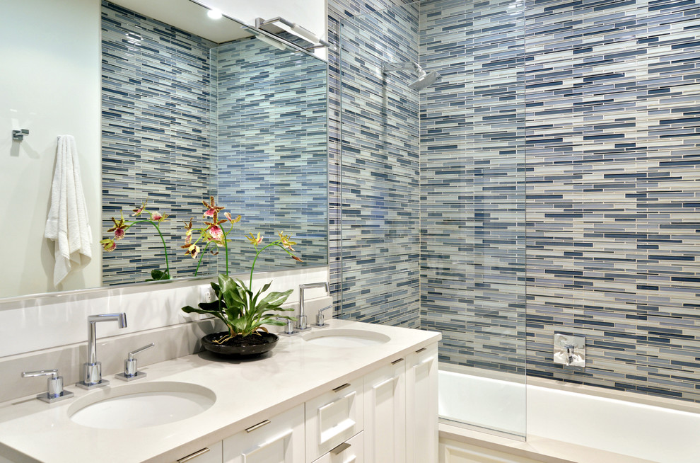 Стильный дизайн: большая главная ванная комната в стиле модернизм с фасадами с утопленной филенкой, белыми фасадами, ванной в нише, душем над ванной, синей плиткой, удлиненной плиткой, синими стенами, врезной раковиной, столешницей из искусственного кварца, бежевым полом и душем с распашными дверями - последний тренд