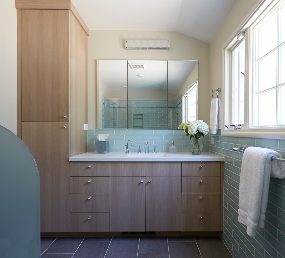 Inspiration for a medium sized retro ensuite bathroom in San Francisco with flat-panel cabinets, medium wood cabinets, an alcove bath, a shower/bath combination, a two-piece toilet, blue tiles, ceramic tiles, beige walls, porcelain flooring, a trough sink and engineered stone worktops.