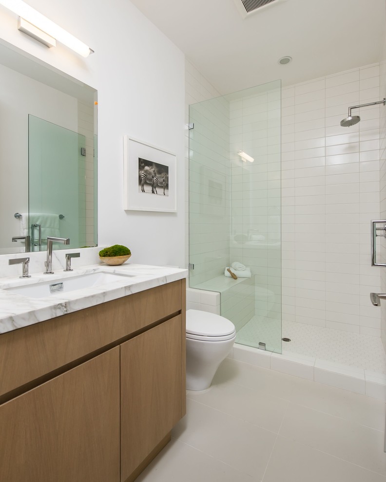 ロサンゼルスにあるラグジュアリーな広いミッドセンチュリースタイルのおしゃれな浴室 (アンダーカウンター洗面器、フラットパネル扉のキャビネット、中間色木目調キャビネット、大理石の洗面台、アルコーブ型シャワー、白い壁、ライムストーンの床、白いタイル) の写真