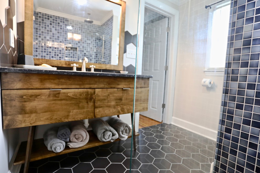 Small retro ensuite bathroom in Raleigh with flat-panel cabinets, medium wood cabinets, a built-in shower, blue tiles, ceramic tiles, beige walls, ceramic flooring, a submerged sink, granite worktops, black floors, an open shower and blue worktops.