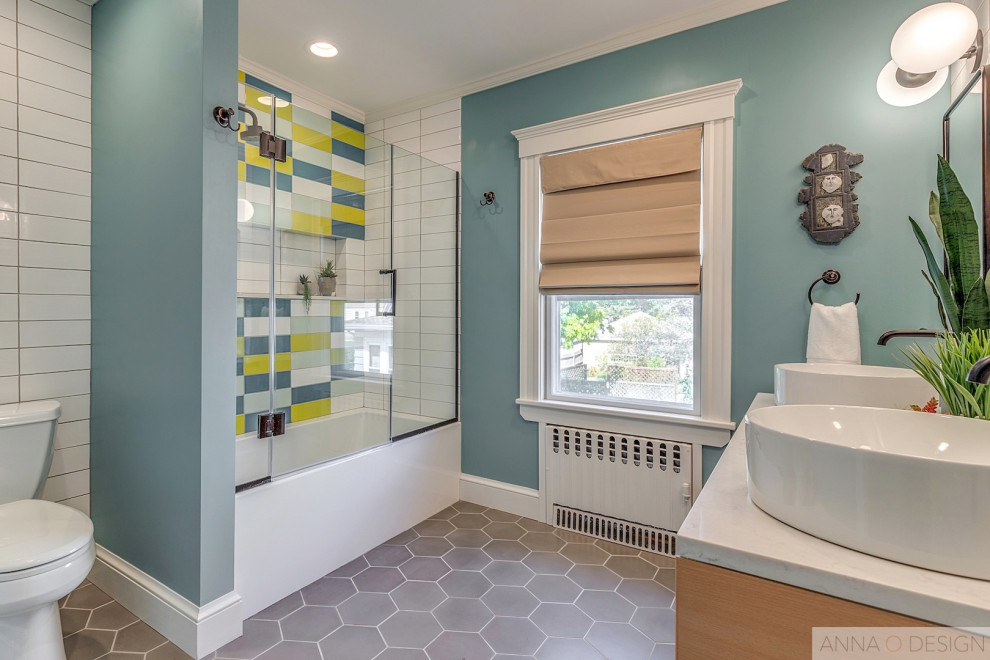 Cette photo montre une salle de bain principale rétro en bois clair de taille moyenne avec un placard en trompe-l'oeil, une baignoire en alcôve, un combiné douche/baignoire, WC séparés, un carrelage blanc, des carreaux de porcelaine, un mur bleu, carreaux de ciment au sol, une vasque, un plan de toilette en surface solide, un sol gris, une cabine de douche à porte battante et un plan de toilette blanc.