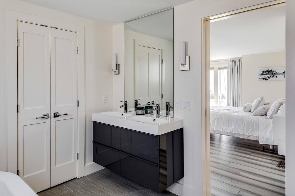 Foto di una grande stanza da bagno padronale stile marinaro con ante lisce, ante nere, vasca freestanding, pareti bianche, lavabo integrato e pavimento grigio