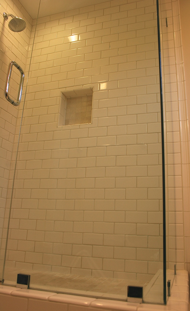Klassisk inredning av ett badrum, med ett undermonterad handfat, möbel-liknande, skåp i mörkt trä, marmorbänkskiva, en hörndusch, en toalettstol med separat cisternkåpa, beige kakel, tunnelbanekakel, beige väggar och travertin golv