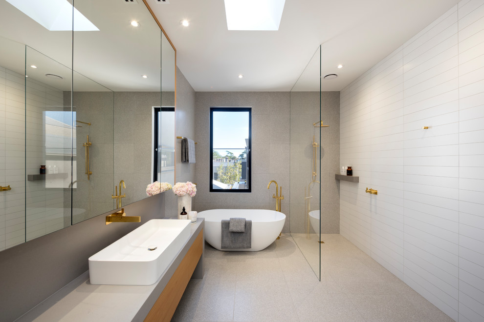 Foto på ett funkis en-suite badrum, med släta luckor, skåp i mellenmörkt trä, ett fristående badkar, våtrum, grå kakel, vit kakel, grå väggar, ett fristående handfat, bänkskiva i betong, grått golv och med dusch som är öppen