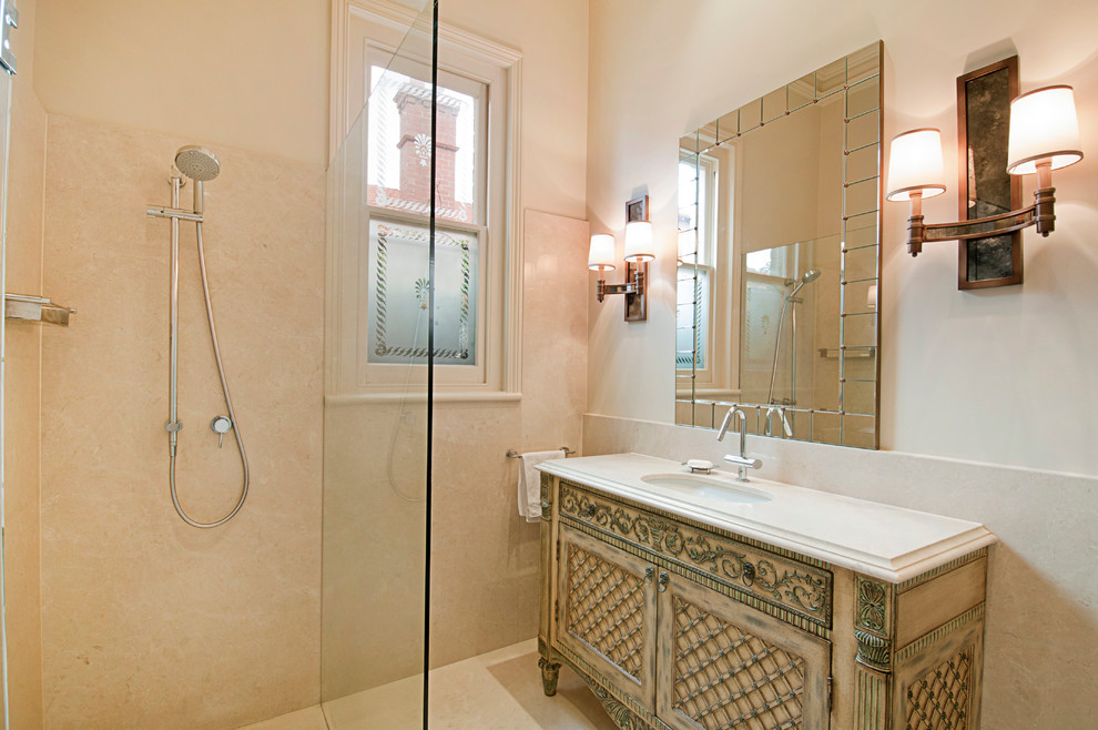Corner shower - mid-sized traditional beige tile and ceramic tile ceramic tile corner shower idea in Melbourne with an undermount sink, furniture-like cabinets, light wood cabinets, limestone countertops, a one-piece toilet and beige walls