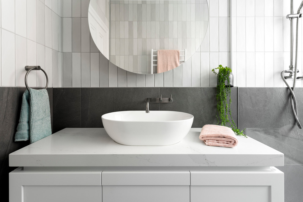 На фото: ванная комната в современном стиле с белыми фасадами, серой плиткой, настольной раковиной и белой столешницей с
