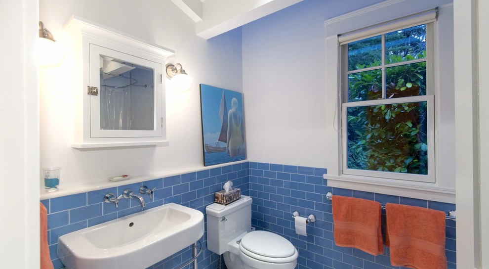 Bild på ett mellanstort maritimt badrum, med luckor med infälld panel, en hörndusch, en toalettstol med separat cisternkåpa, blå kakel, porslinskakel, vita väggar, klinkergolv i porslin, ett nedsänkt handfat och granitbänkskiva