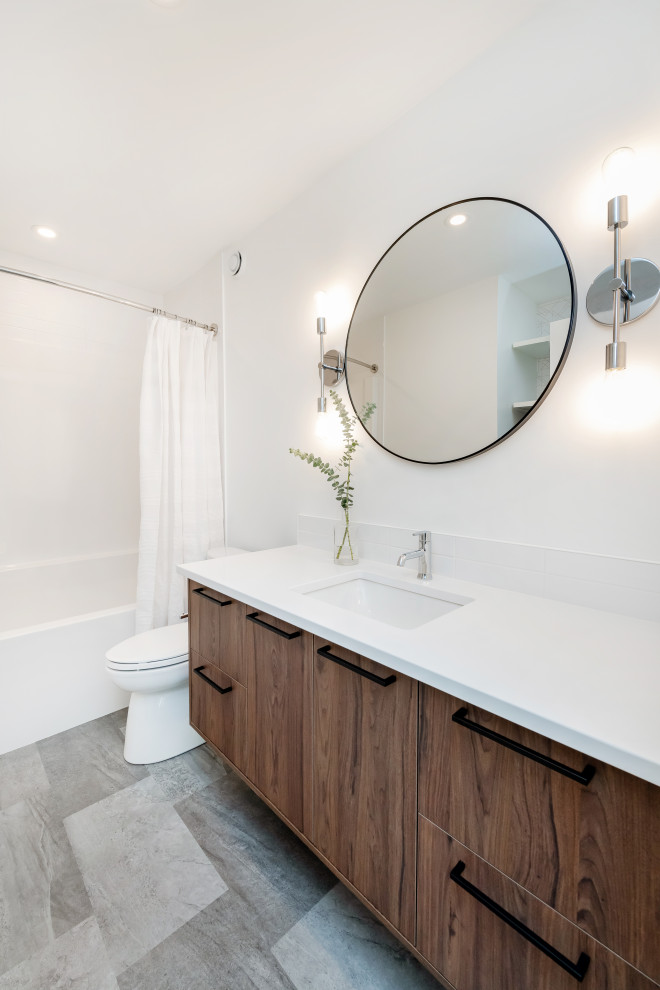 Foto de cuarto de baño retro, grande, con armarios con paneles lisos, puertas de armario marrones, combinación de ducha y bañera, sanitario de dos piezas, baldosas y/o azulejos blancos, baldosas y/o azulejos de cerámica, paredes blancas, suelo vinílico, lavabo bajoencimera, encimera de cuarzo compacto, suelo gris, ducha con cortina y encimeras blancas