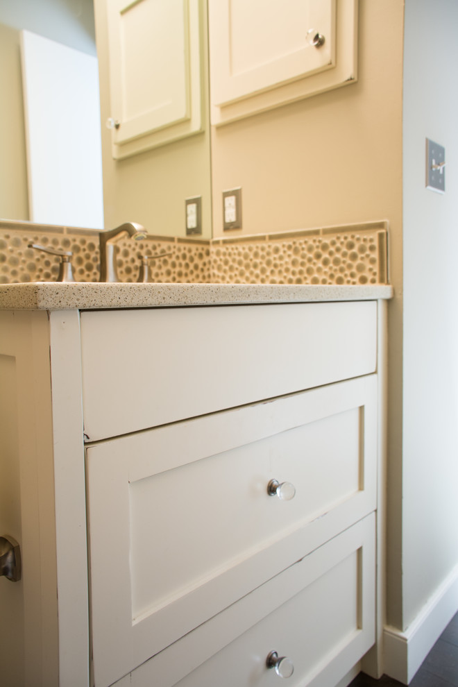 This is an example of a small traditional ensuite bathroom in Calgary with shaker cabinets, distressed cabinets, a two-piece toilet, beige tiles, ceramic tiles, beige walls, dark hardwood flooring, a submerged sink and engineered stone worktops.