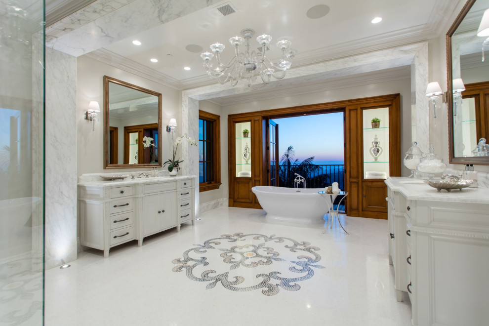 Inspiration for a mediterranean ensuite bathroom in Orange County with white cabinets, a freestanding bath, white tiles, white walls, marble flooring, a submerged sink, marble worktops, white floors, white worktops and recessed-panel cabinets.