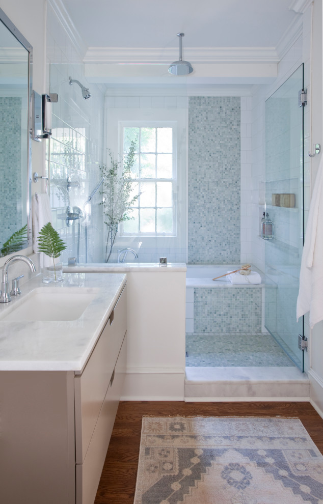 Cette image montre une salle de bain traditionnelle avec un placard à porte plane, des portes de placard grises, une baignoire encastrée, un espace douche bain, un carrelage blanc, un mur blanc, un sol en bois brun, un lavabo encastré, un sol marron, un plan de toilette blanc, meuble simple vasque et meuble-lavabo suspendu.