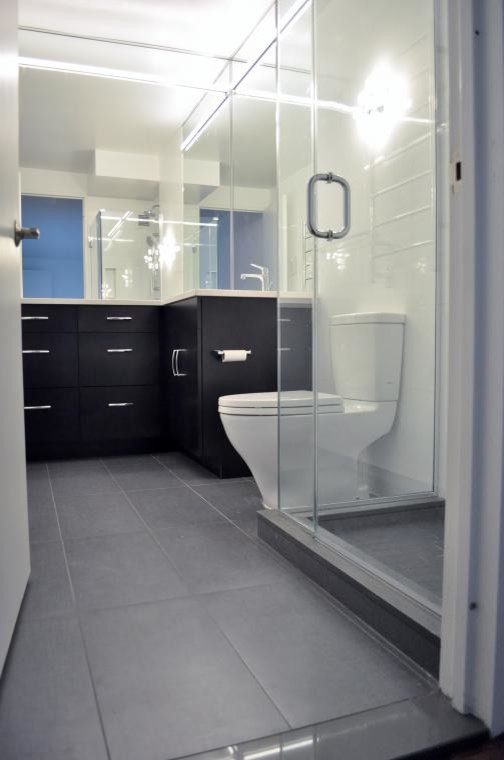 Diseño de cuarto de baño minimalista pequeño con armarios con paneles lisos, puertas de armario de madera en tonos medios, ducha esquinera, baldosas y/o azulejos grises y paredes blancas