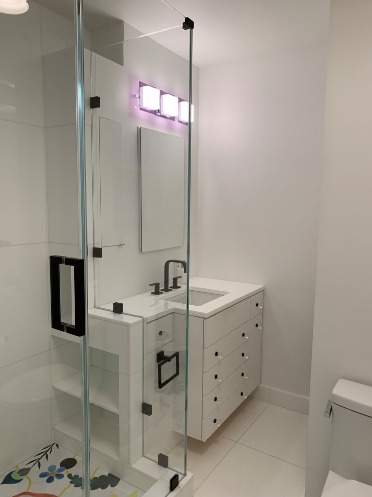 Идея дизайна: маленькая главная ванная комната в стиле модернизм с плоскими фасадами, белыми фасадами, угловым душем, унитазом-моноблоком, белой плиткой, стеклянной плиткой, белыми стенами, полом из керамогранита, врезной раковиной, стеклянной столешницей, белым полом, душем с распашными дверями, белой столешницей, нишей, тумбой под одну раковину и встроенной тумбой для на участке и в саду