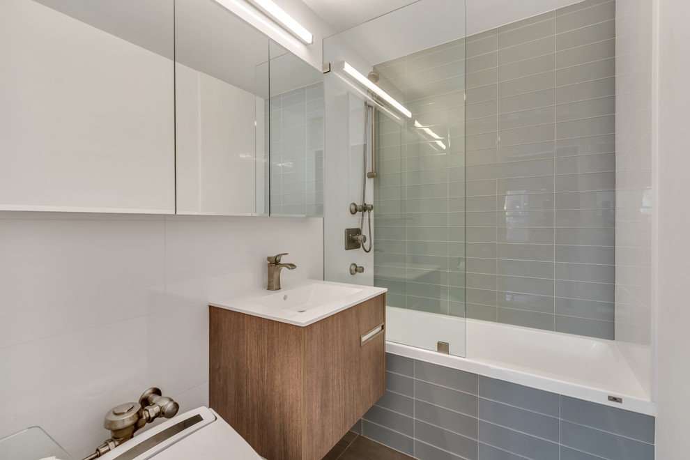 Example of a small minimalist master green tile and glass tile ceramic tile and black floor bathroom design in New York with flat-panel cabinets, brown cabinets, a one-piece toilet, gray walls, a drop-in sink and quartzite countertops