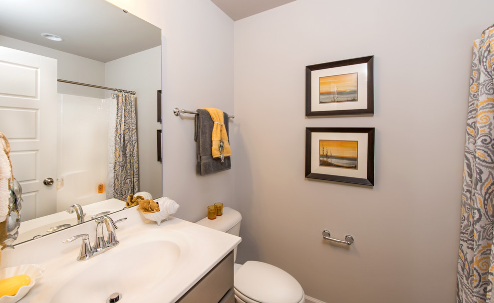 Diseño de cuarto de baño clásico renovado de tamaño medio con armarios con paneles lisos, puertas de armario marrones, bañera empotrada, combinación de ducha y bañera, sanitario de dos piezas, paredes grises y lavabo integrado