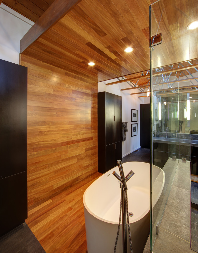 Стильный дизайн: главная ванная комната в стиле лофт с плоскими фасадами, темными деревянными фасадами, столешницей из бетона, отдельно стоящей ванной и серой плиткой - последний тренд