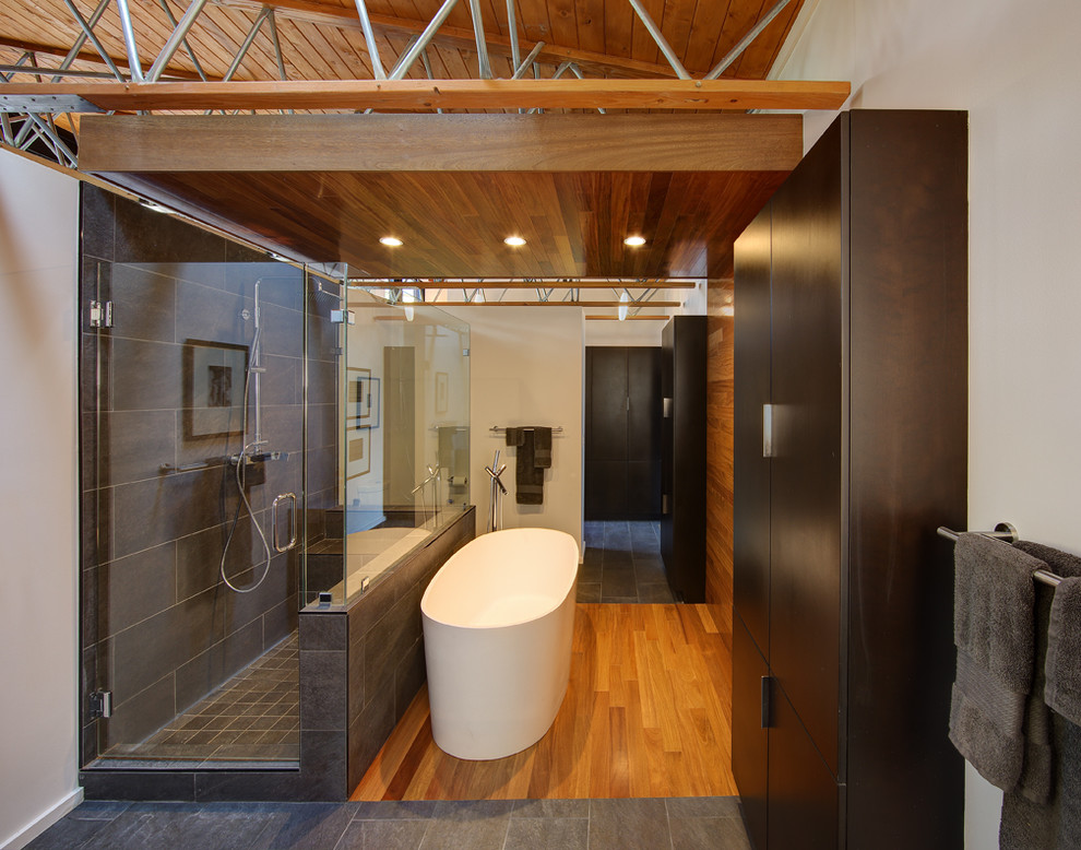 他の地域にあるコンテンポラリースタイルのおしゃれな浴室 (濃色木目調キャビネット、置き型浴槽、茶色いタイル) の写真