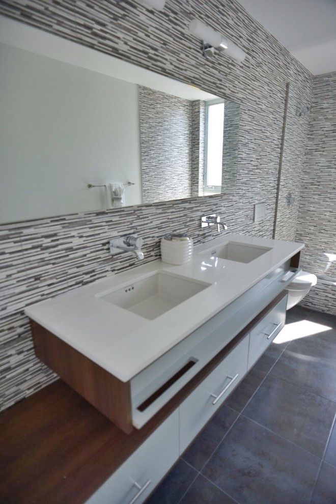 Example of a huge minimalist 3/4 multicolored tile and porcelain tile porcelain tile bathroom design in Los Angeles with a drop-in sink, flat-panel cabinets, dark wood cabinets, quartzite countertops, a wall-mount toilet and white walls