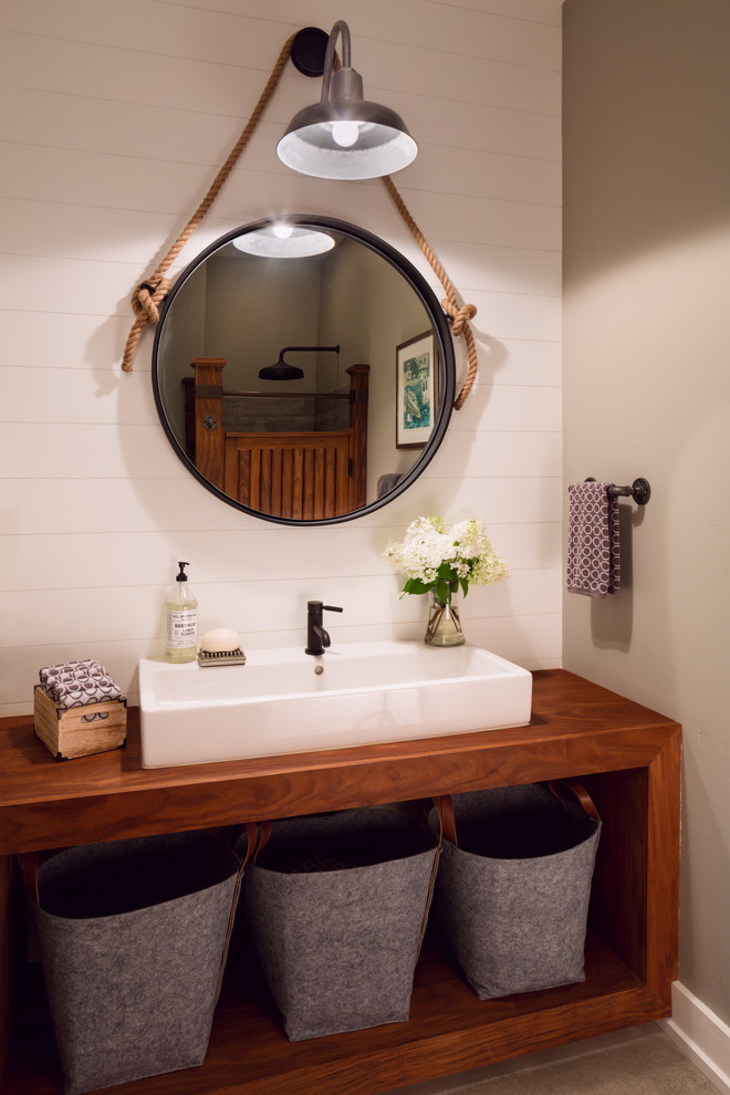 Example of a country bathroom design in Milwaukee with open cabinets, dark wood cabinets, beige walls and a trough sink