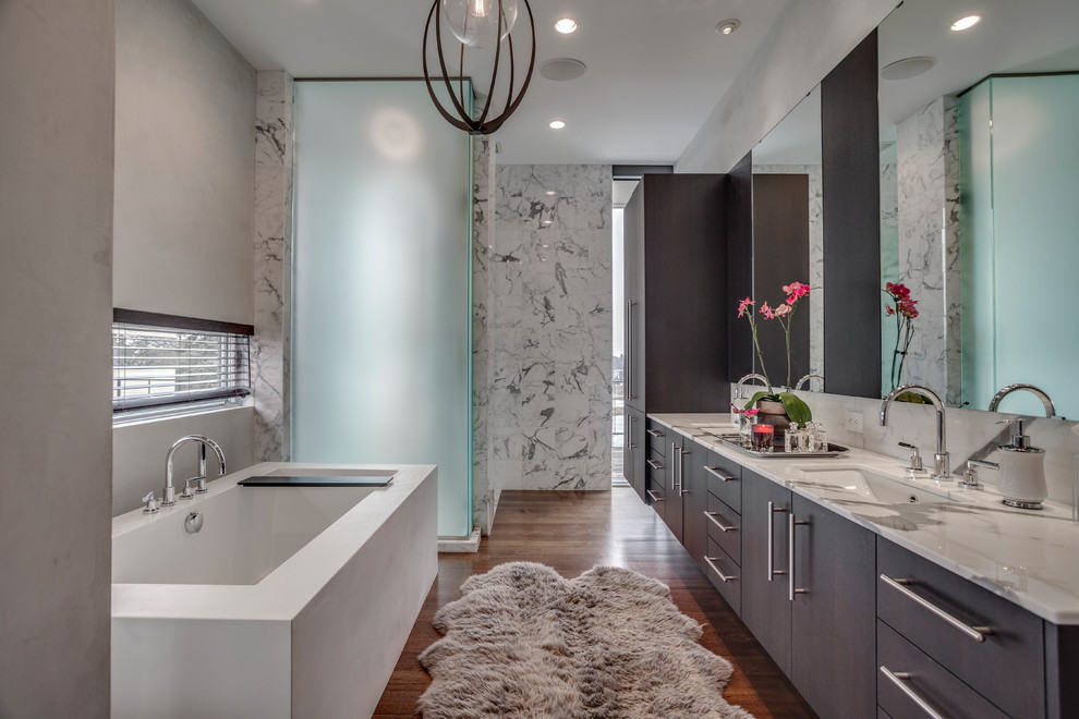 Ispirazione per una stanza da bagno padronale design con ante lisce, ante in legno bruno, vasca da incasso, doccia alcova, piastrelle grigie, piastrelle di marmo, pavimento in legno massello medio, lavabo integrato, top in marmo, pavimento marrone e porta doccia a battente