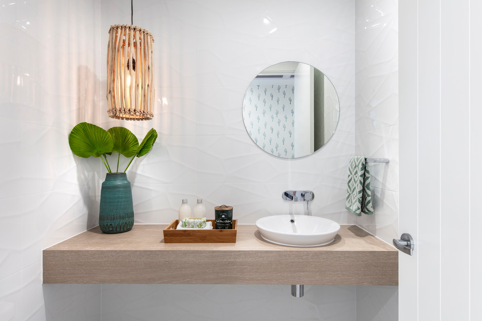 На фото: ванная комната в морском стиле с белой плиткой, белыми стенами, настольной раковиной и коричневой столешницей с