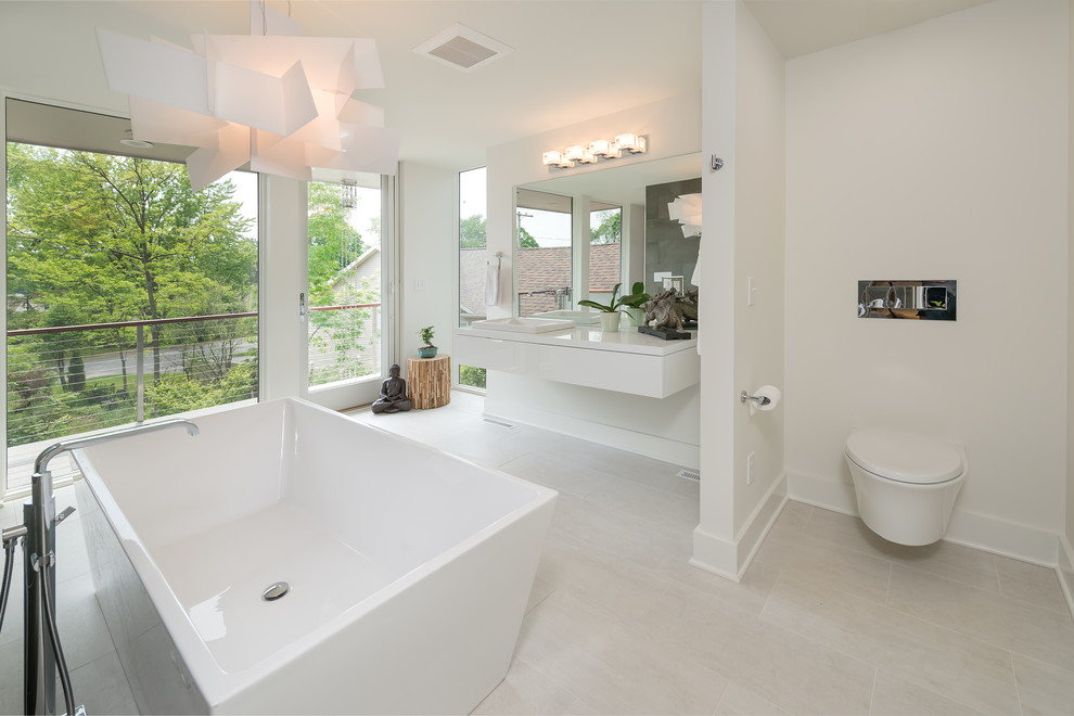 Стильный дизайн: большая главная ванная комната в стиле модернизм с плоскими фасадами, белыми фасадами, отдельно стоящей ванной, инсталляцией, белыми стенами, полом из ламината, накладной раковиной, столешницей из ламината и серым полом - последний тренд