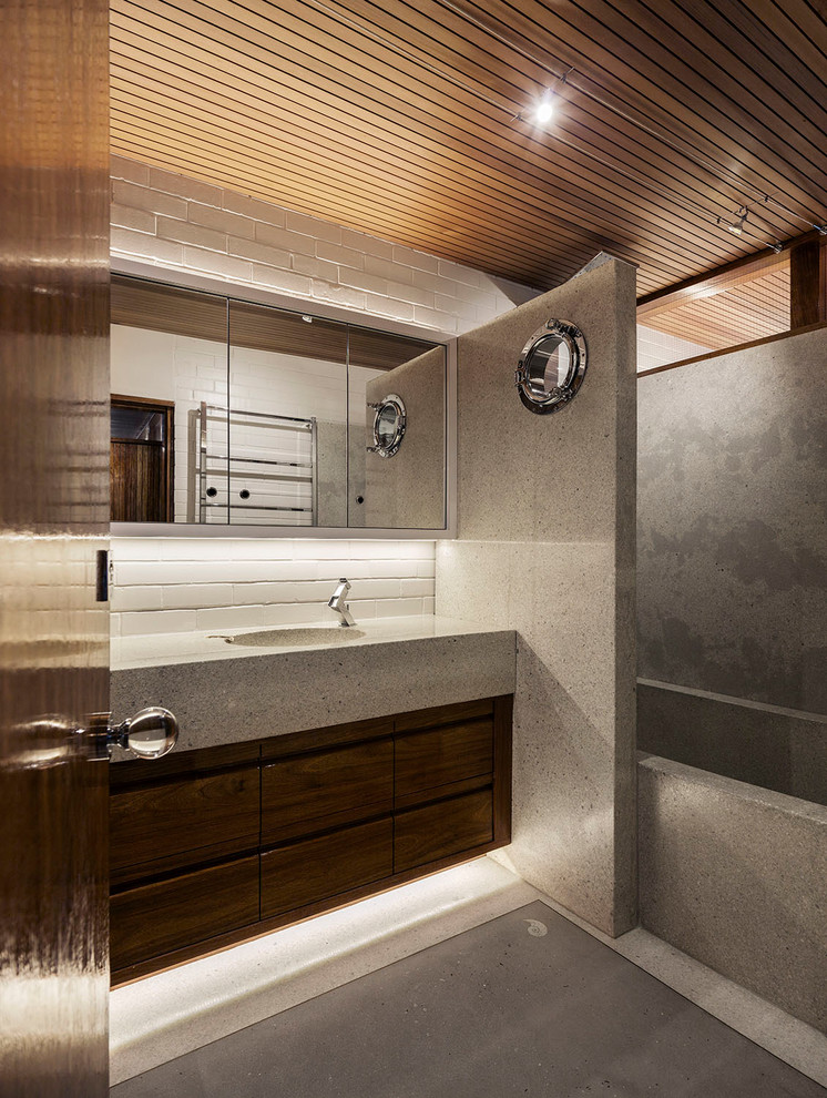Inspiration for a medium sized retro ensuite bathroom in Auckland with recessed-panel cabinets, dark wood cabinets, a built-in bath, a shower/bath combination, a one-piece toilet, grey tiles, stone slabs, white walls, terrazzo flooring, an integrated sink, terrazzo worktops, grey floors and an open shower.