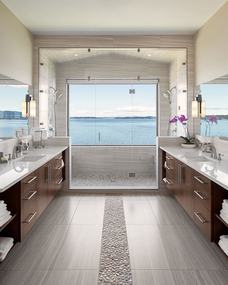На фото: главная ванная комната в современном стиле с плоскими фасадами, темными деревянными фасадами, двойным душем, бежевыми стенами, полом из галечной плитки, врезной раковиной и зеркалом с подсветкой с