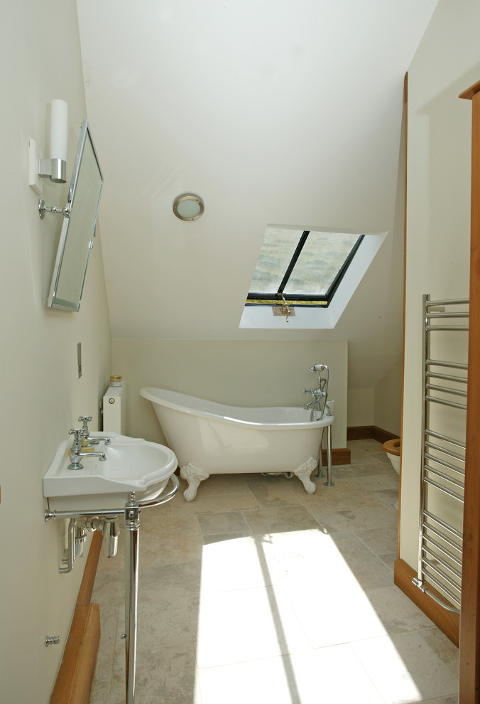 Lantlig inredning av ett badrum, med ett konsol handfat, ett badkar med tassar, beige kakel, vita väggar och klinkergolv i porslin