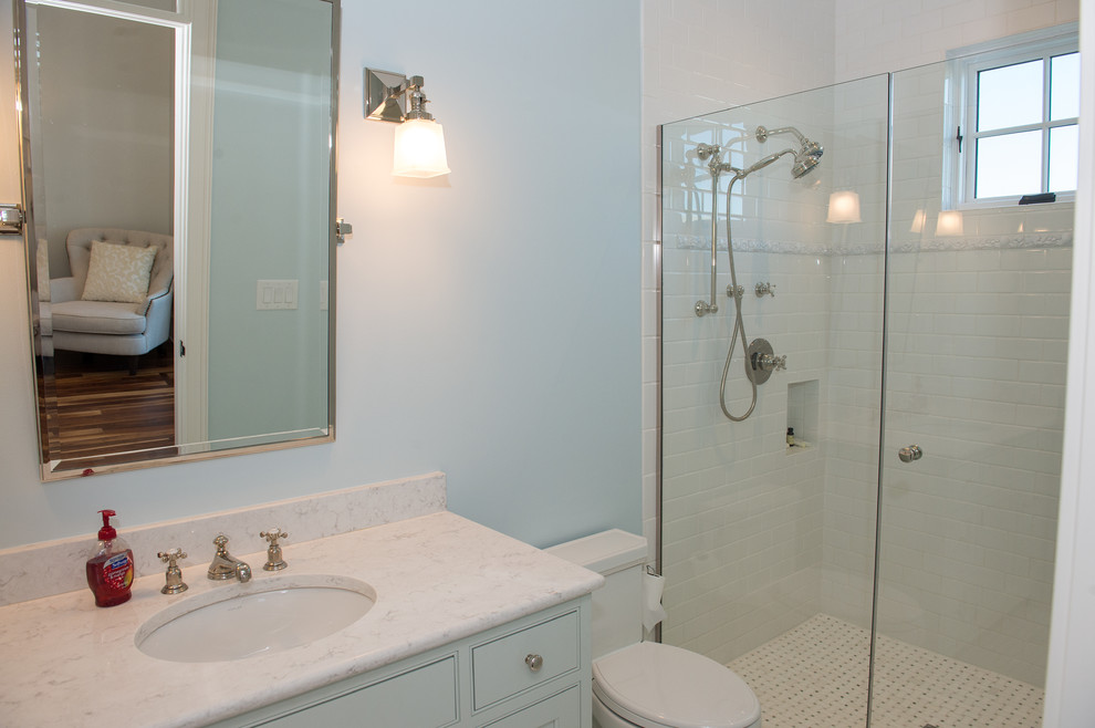 Idéer för att renovera ett mellanstort maritimt badrum med dusch, med möbel-liknande, vita skåp, en dusch i en alkov, en toalettstol med separat cisternkåpa, vit kakel, keramikplattor, blå väggar, ett undermonterad handfat, bänkskiva i kvarts och dusch med gångjärnsdörr