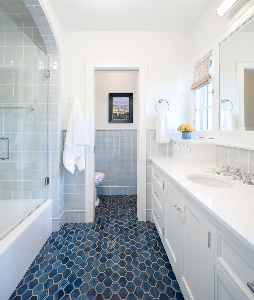 Photo of a classic bathroom in Minneapolis with recessed-panel cabinets, white cabinets, an alcove bath, a shower/bath combination, grey tiles, white walls, a submerged sink, blue floors and white worktops.